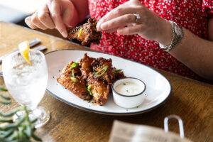 Plated wings on a white dish with one being picked up