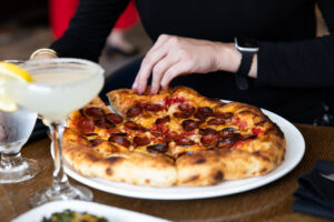 Woman picking up pepperoni pizza slice